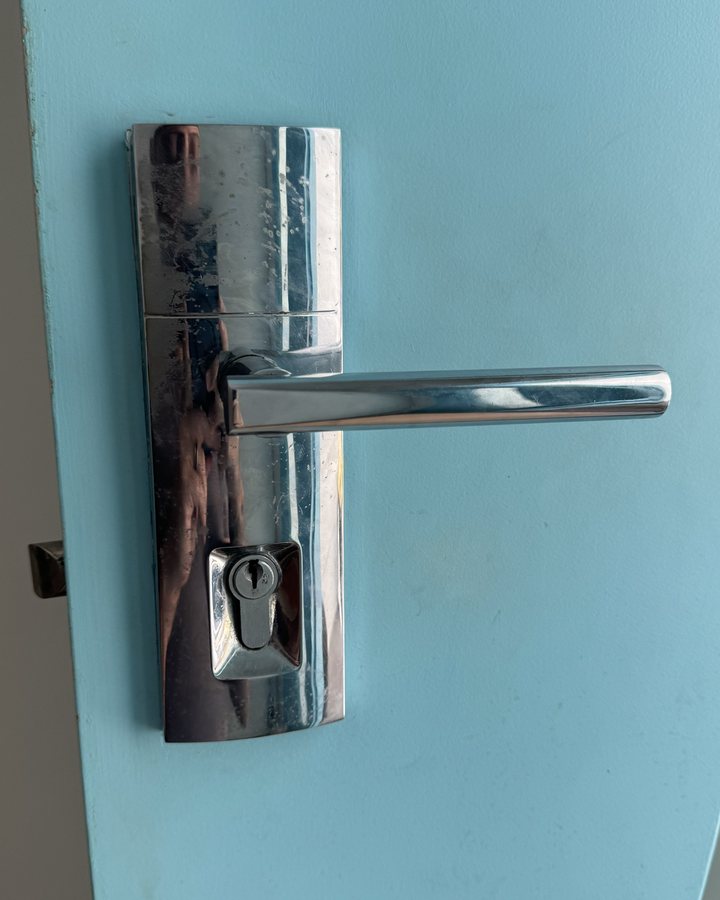 Old lever handle and key lock on a front door, before